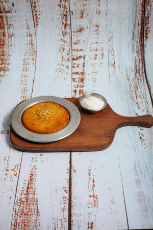 A rich dessert is presented on a wooden board, accompanied by a small bowl of cream. The dessert...