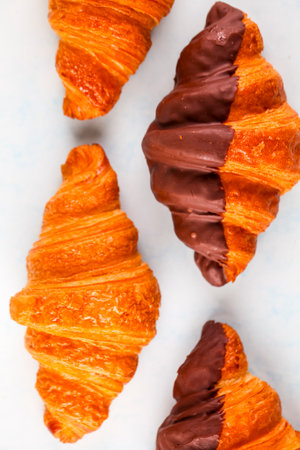 Freshly baked croissants are elegantly arranged, showing their flaky layers and rich chocolate dip. A tempting treat for pastry lovers at any time.の写真素材