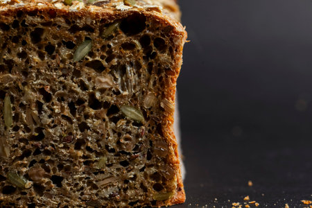 Close-up view of freshly baked whole grain bread, featuring a dense texture and visible seeds,...