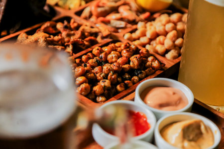 Various snacks are arranged on a wooden platter alongside drinks, creating a lively atmosphere for friends to enjoy. Dips and nuts add flavor to the experience.の写真素材