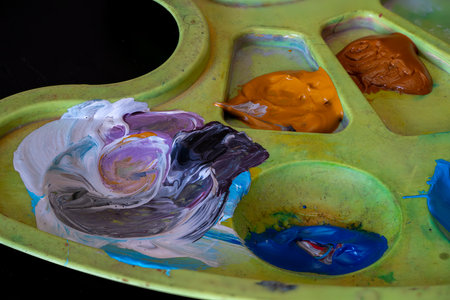 A close view of a paint palette filled with a variety of colors, including purple, blue, and orange. The artist is preparing for a creative session in the studio.の写真素材