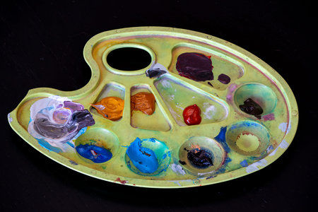 The paint palette holds multiple colors, blending vibrant and muted shades in a circular...
