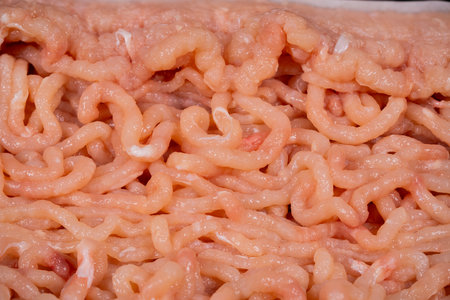 Close-up view of freshly ground meat displaying its fine texture and color. The meat is prepared and ready for cooking in a kitchen environment.の写真素材