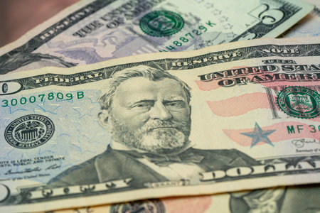 Detailed view of fifty-dollar bills stacked together, highlighting the intricate designs and...