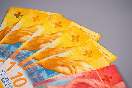 A collection of Swiss 10 franc banknotes shows hands holding the currency. This scene takes place in a finance-related environment with a simple backdrop.の写真素材