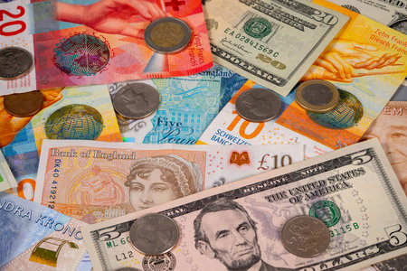 Different types of paper bills and coins from multiple countries are placed on a flat surface. The...