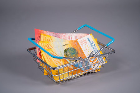 A small shopping basket holds various Swiss franc notes. The currency is stacked inside, ready for...