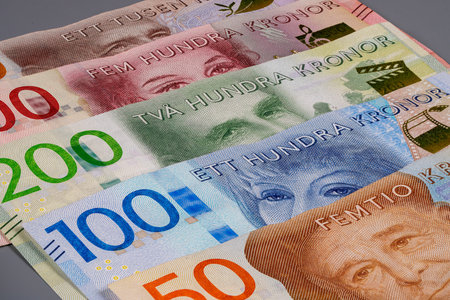 Several Swedish banknotes are arranged in a line on a flat surface. The notes feature different colors and designs that represent various values of kronor.の写真素材