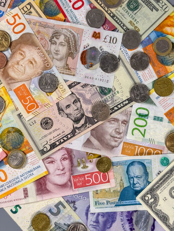 Many different banknotes and coins are spread out on a flat surface. Notes from various countries...