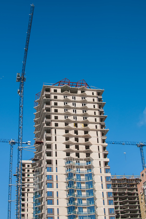 High white building surrounded by construction cranesの写真素材