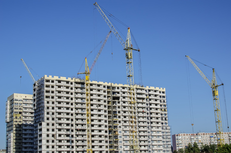 Group of residential high-rise cranes on the sky background and white buildings.の写真素材