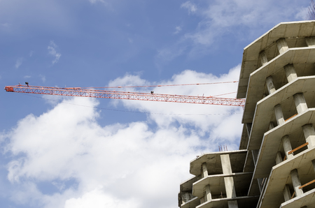 Arrow construction crane against the sky and the concrete homesの写真素材