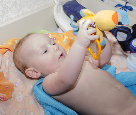 The boy at the age of 6 months lying down holding a toyの写真素材