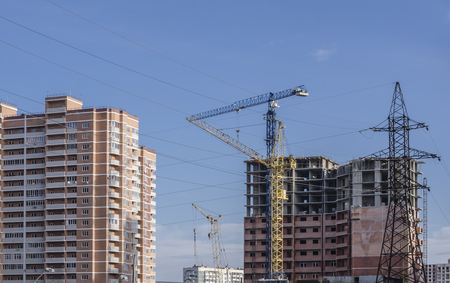 High-voltage masts against the background of high-rise buildings under constructionの写真素材