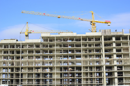 Two yellow cranes above the building under construction.の写真素材