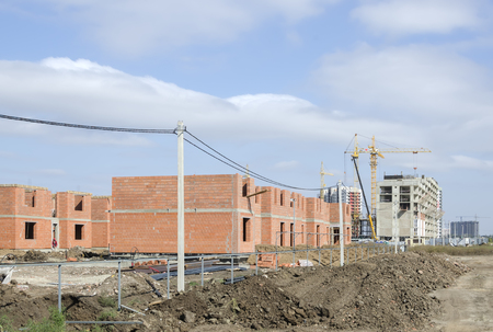 Under construction cottages made of brown bricks against the sky.の写真素材