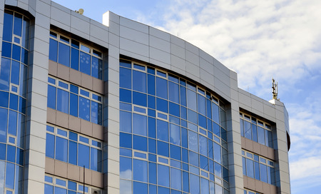 Close-up of blue glass wall of the new building on sky backgroundの写真素材