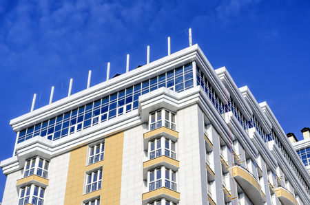 White house with yellow balcony against the sky.の写真素材