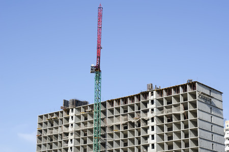 The red construction crane against the background of the sky and the building under construction.の写真素材
