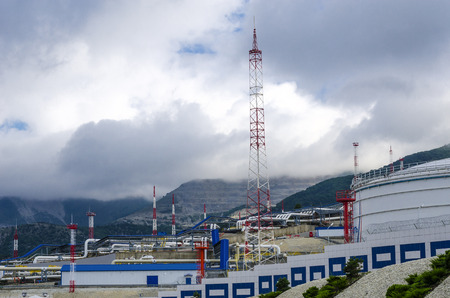 The oil reservoir is surrounded by lightning protection towers and pipelines against the background of mountains.の写真素材
