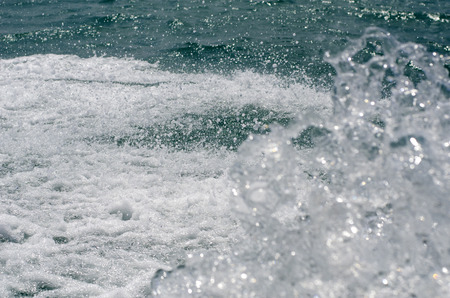 Background of a bluish-green sea surface with splashes and waves.の写真素材