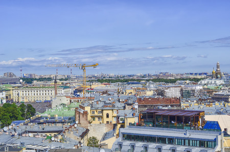 View of the city from above. Multi-colored buildings, shop windows, roofs, domes, in the center of the construction crane.の写真素材