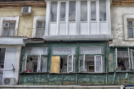 Front part of an old wooden two-story house with a modern plastic balcony and air conditioning.の写真素材