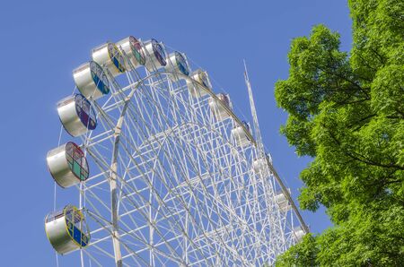 "Ferris wheel" against the blue sky and green treeの写真素材