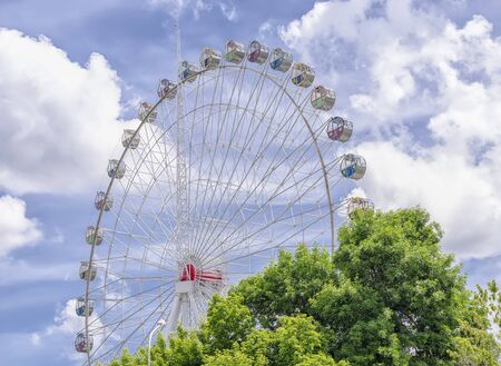 Attraction against a cloudy blue sky over green treesの写真素材