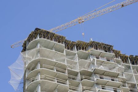 Boom crane over the roof of a building under construction against the sky.の写真素材