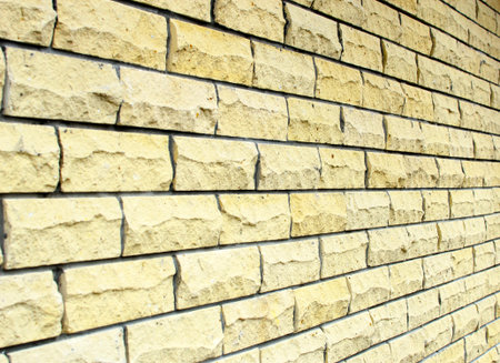 Background wall of yellow rectangular natural stone. Side angle view.