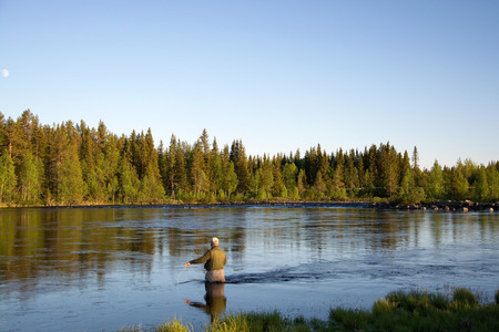 Angler during fly fishing in a river at the evening.の写真素材