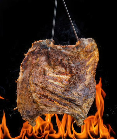 Piece of pork meat on fire isolated on black background, close upの写真素材