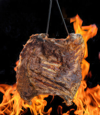 Piece of meat on a hook on a black background.の写真素材