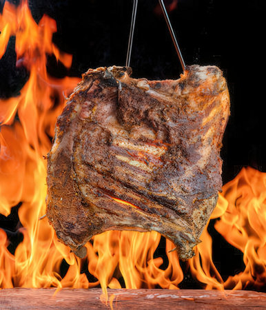 Grilled pork ribs on a barbecue grill with flames on a black backgroundの写真素材
