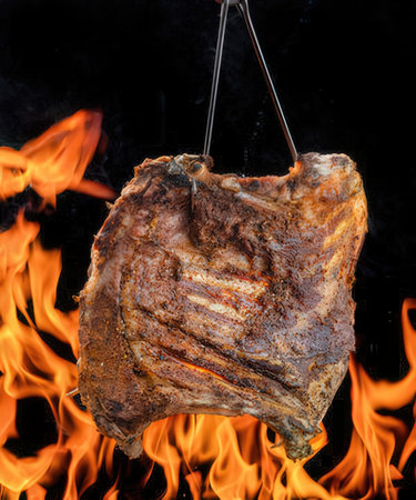 Piece of pork meat on a spit with flames on a black backgroundの写真素材