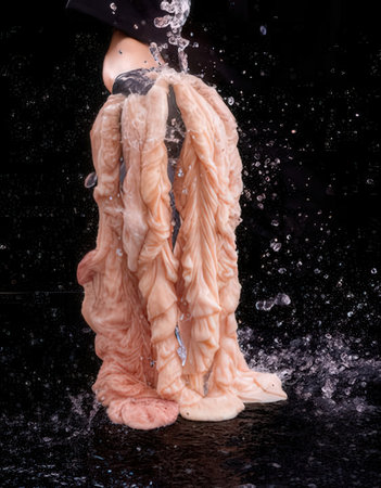 woman's hand holding a piece of meat in water on black backgroundの写真素材