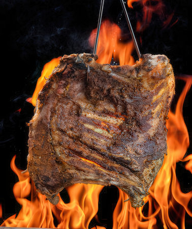 Grilled ribs on a barbecue grill with flames on a black backgroundの写真素材