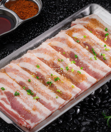 Raw pork belly with garlic and soy sauce on black stone background.の写真素材