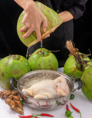 Coconut and chicken in a cooking pot on a black backgroundの写真素材