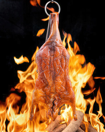 Whole chicken on a hook in flames on a black backgroundの写真素材
