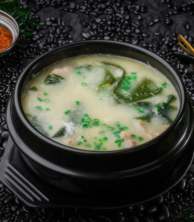 Miso soup with seaweed in black pot on black backgroundの写真素材
