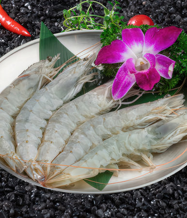 Fresh shrimp on white plate with red chili pepper on black stone backgroundの写真素材