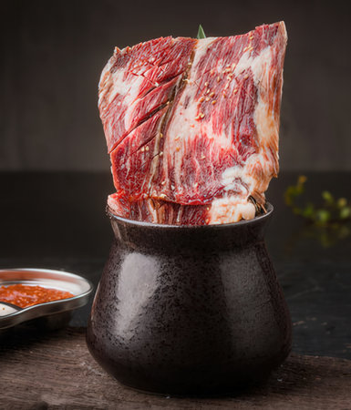 Raw fresh meat with spices and herbs in a black ceramic pot.の写真素材