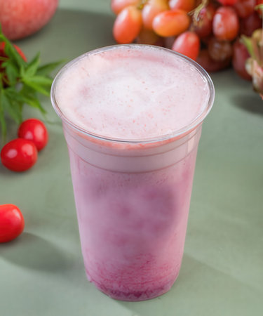 A cup of smoothie with fruits on a green background.の写真素材