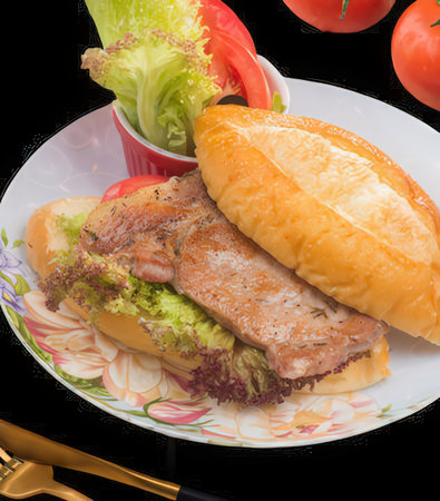 Sandwich with fried pork, lettuce and tomato on a black backgroundの写真素材