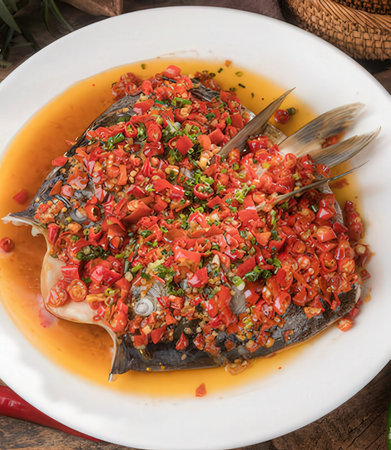 Steamed fish with spicy sauce and chilli on white plate.の写真素材