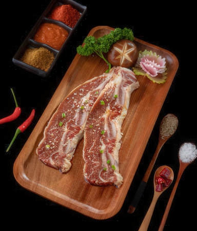 Raw slab of beef on wooden cutting board isolated on black backgroundの写真素材