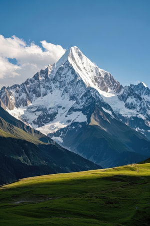 Mountain landscape with green meadow and snow-capped peaksの素材