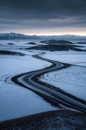 Icelandic landscape with a winding road and snow covered mountains.の素材